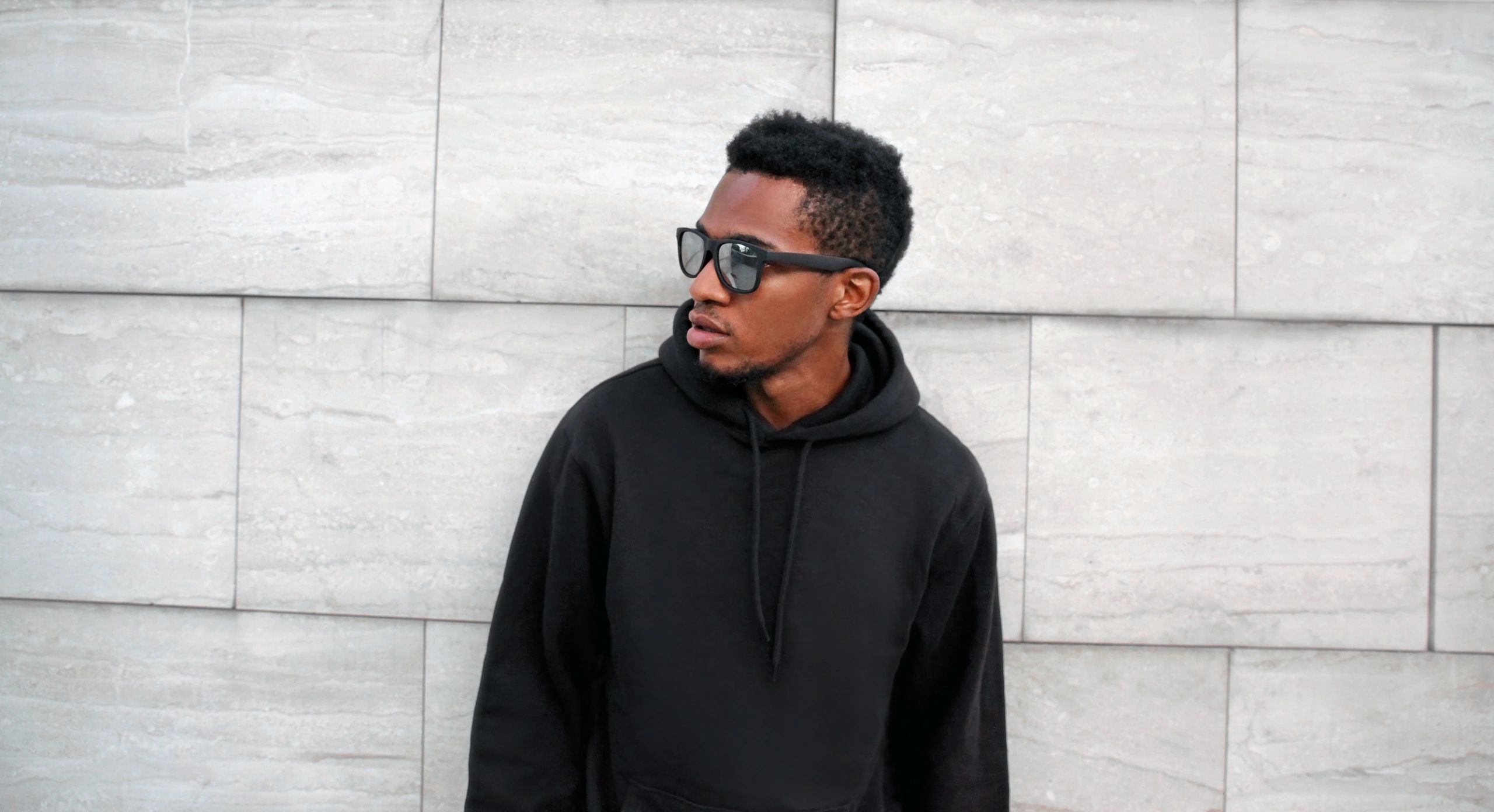 Black man in a hoodie and sunglasses on a city street
