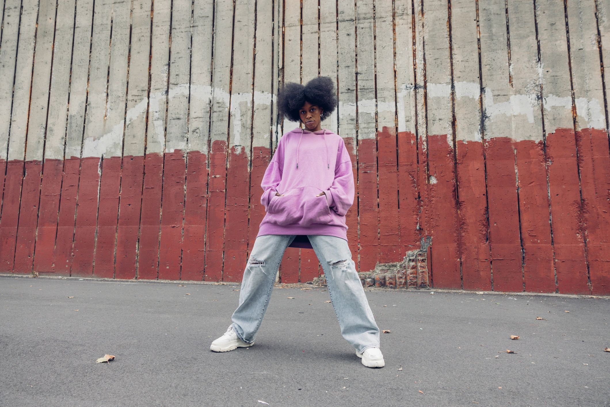 Black woman in streetwear posing against a bold red wall
